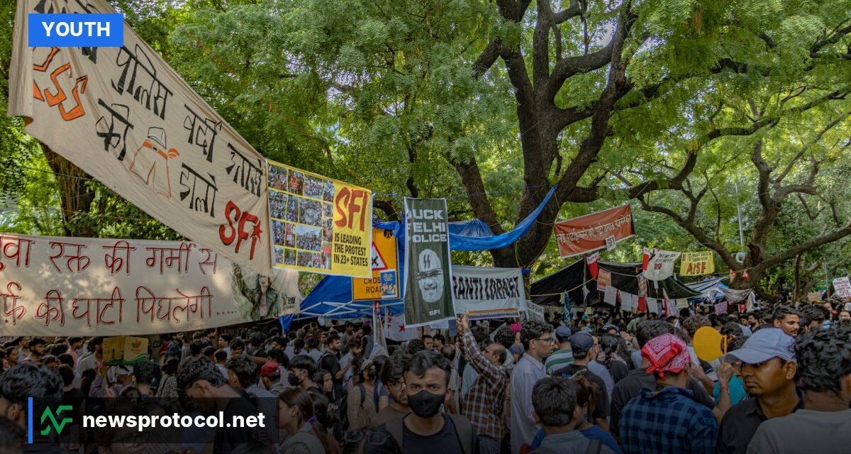 Young Indian demonstrators holding satirical signs during a 2026 protest in New Delhi