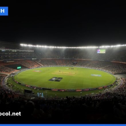 A brightly lit cricket stadium at night during a Twenty20 match with a packed audience.