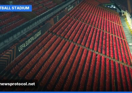An empty football stadium with red seats, ready for a match under clear skies.
