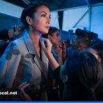 ** Backstage view of a fashion runway with models and lighting rigs. **