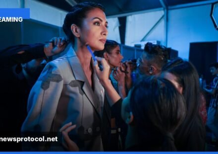 ** Backstage view of a fashion runway with models and lighting rigs. **